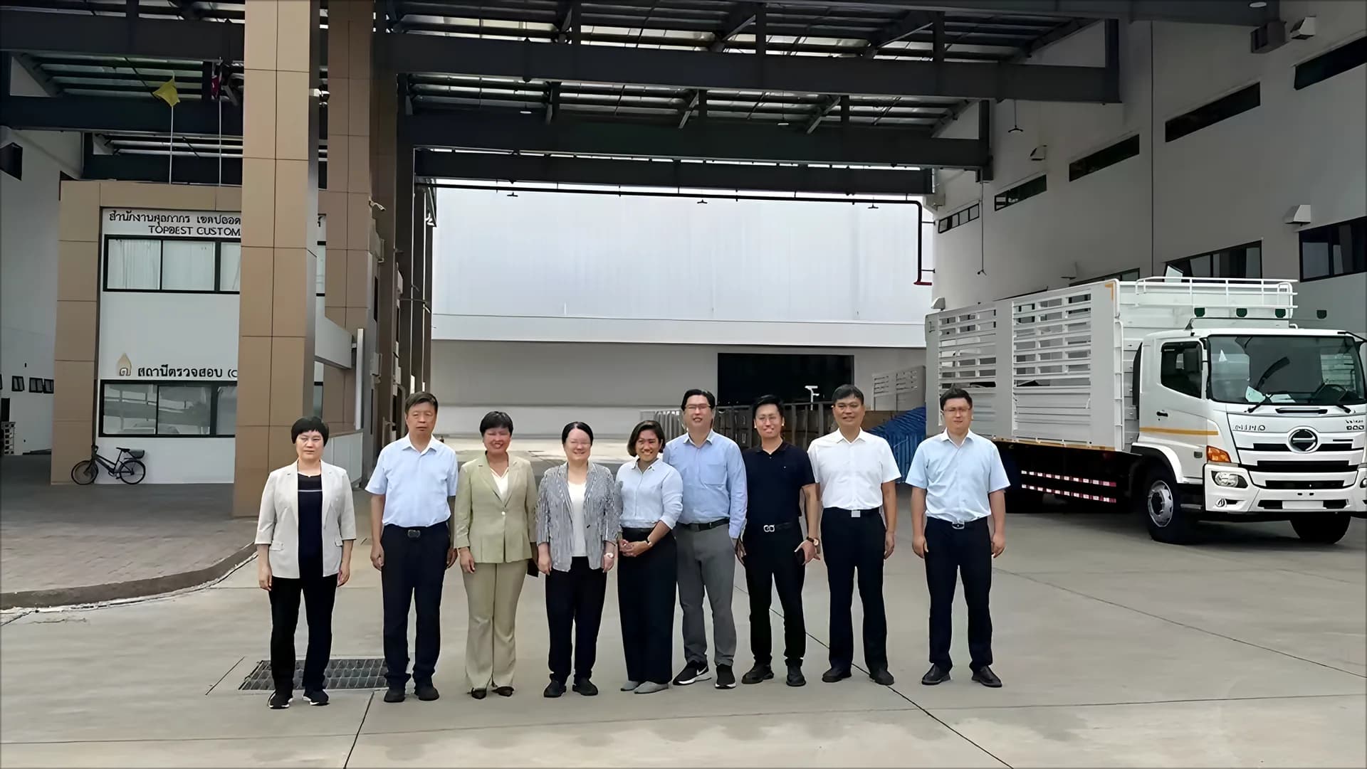 来访人员在厂房入口与货车旁合影