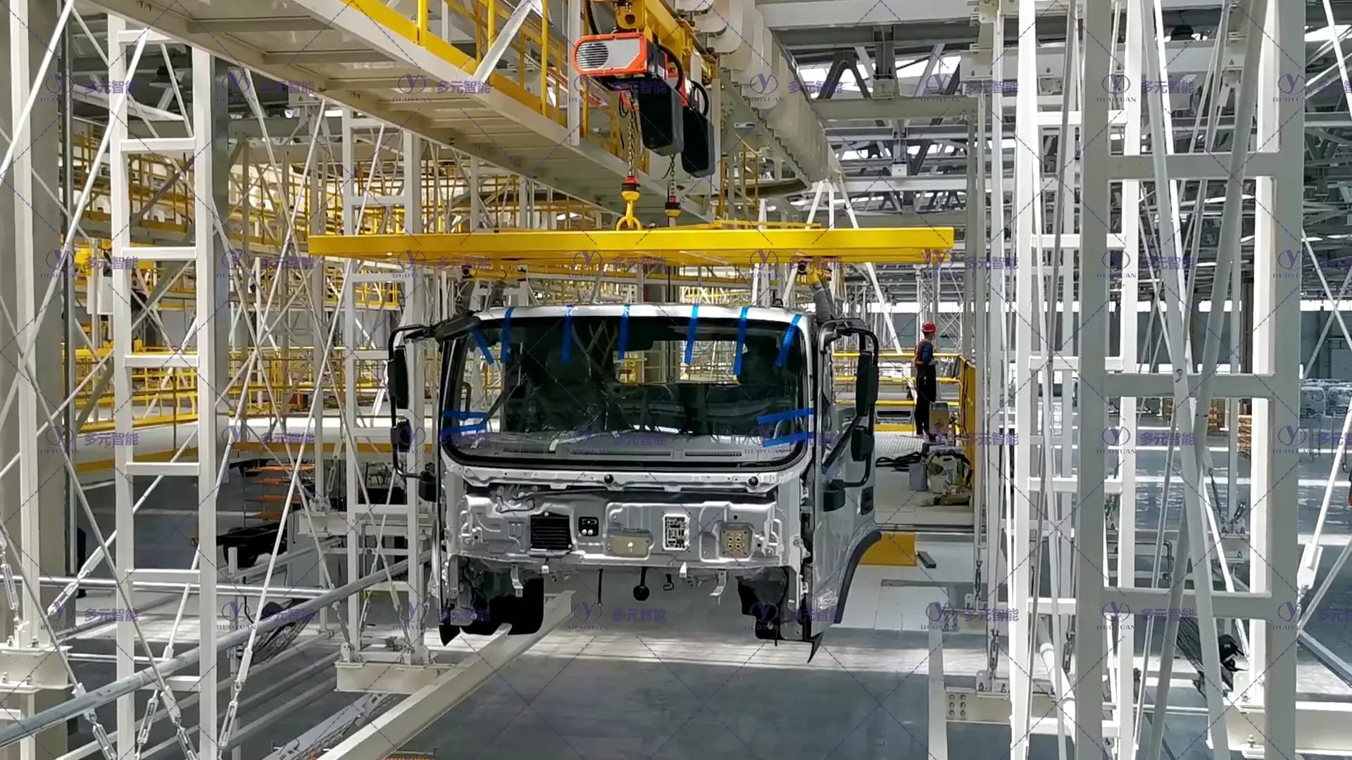 重卡驾驶室在黄色EMS吊具内沿车间轨道输送